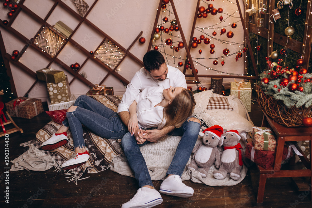 Happy cheerful family hugging each other and smiling together in cozy new year decorated home with christmas eve and lights. Family, christmas holidays concept