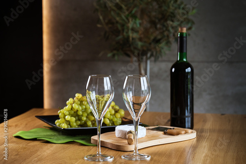 Pouring White wine with branches of grapes on a wooden table.