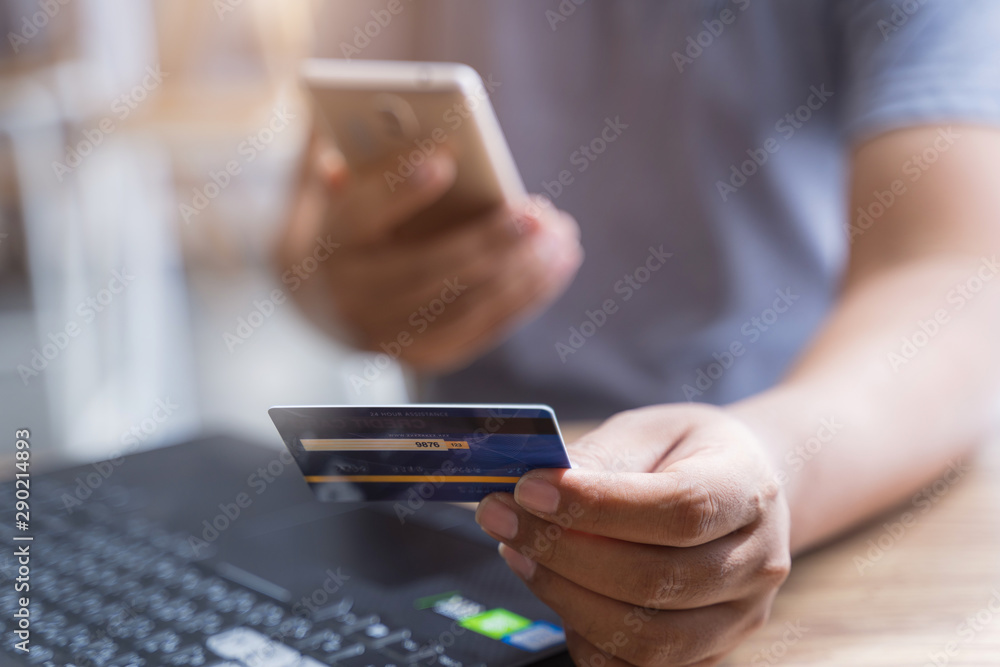 Man using mobile phone and laptop for shopping online by credit card. Pays for purchase.online shopping, online payment,buy and sell products & services. Man using mobile phone and laptop for shopping online by credit card. Pays for purchase.online shopping, online payment,buy and sell products & services.