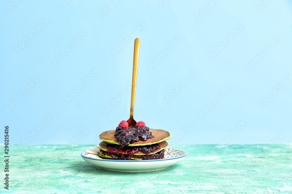 Plate with green pancakes and berry jam on table Plate with green pancakes and berry jam on table