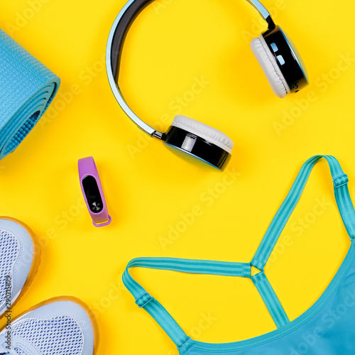 Layout of sport clothes and accessories for women with fruits on yellow background.