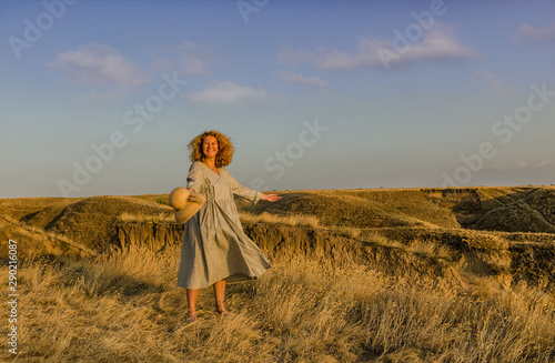 amazing girl in a hat at sunset in the steppe on the sea