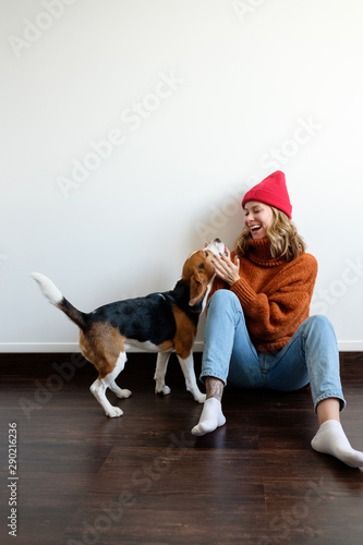 Girl in a sweater at home plays with a dog