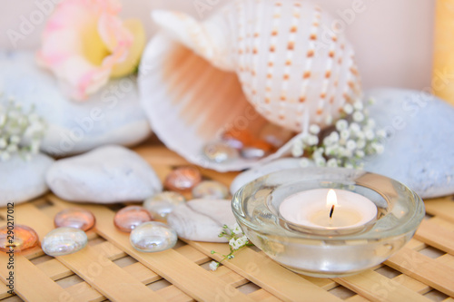 Beautiful burning candle with spa stones and seashell on table