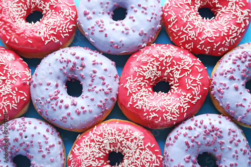 Different tasty donuts on color background