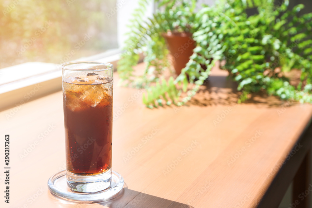 Glass of cold cola on wooden window sill Glass of cold cola on wooden window sill