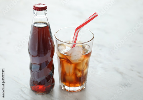 Glass and bottle of cold cola on table