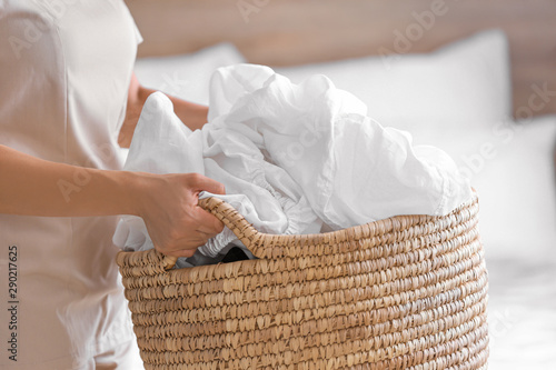 Woman holding basket with laundry in bedroom