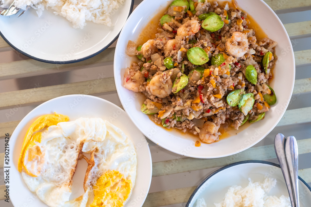 top view of traditional thai style food Spicy stir-fried shrimp with bitter or twisted cluster or stink bean ( sataw ) and shrimp paste on wooden table , Southern thai food. top view of traditional thai style food Spicy stir-fried shrimp with bitter or twisted cluster or stink bean ( sataw ) and shrimp paste on wooden table , Southern thai food.
