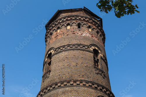 Old red brick tower with windows of different sizes against a blue sky