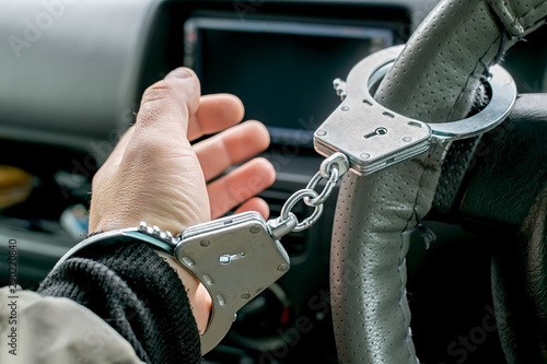 car driver s hand handcuffed to steering wheel  arrest  driving ban by traffic violator