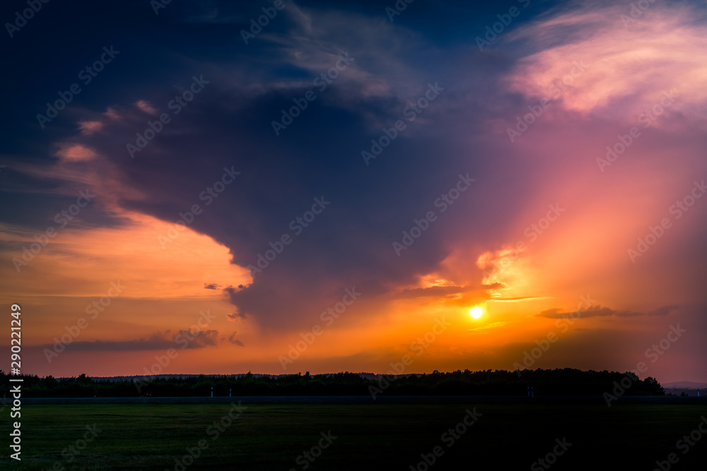 A stormy sunset with dark clouds over a rural pasture landscape.