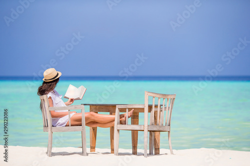 Young woman reading at outdoor beach cafe