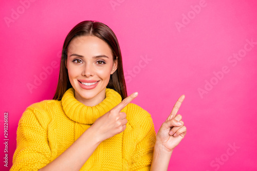 Close up photo of charming youth showing ads with her fingers wearing yellow sweater isolated over fuchsia background
