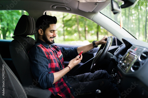 Indian man drive car while hand holding smartphone to use online application. © F8  \ Suport Ukraine