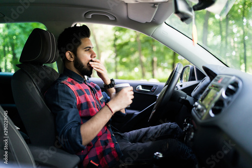 Transportation and vehicle concept. Indian man drinking coffee while driving the car © F8  \ Suport Ukraine