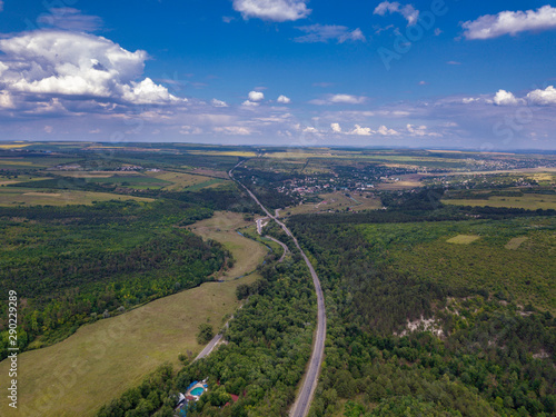 Aerial view of a provincial road passing through a forest and green lands