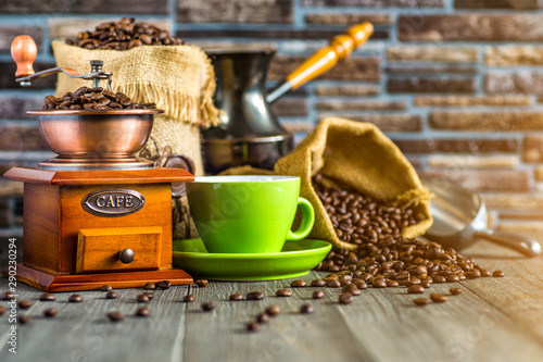 still life with coffee beans and old coffee mill on the wooden background,coffee grinder,coffee accessories brown clay cup vintage wooden mill and sack with beans scoop on old wood background