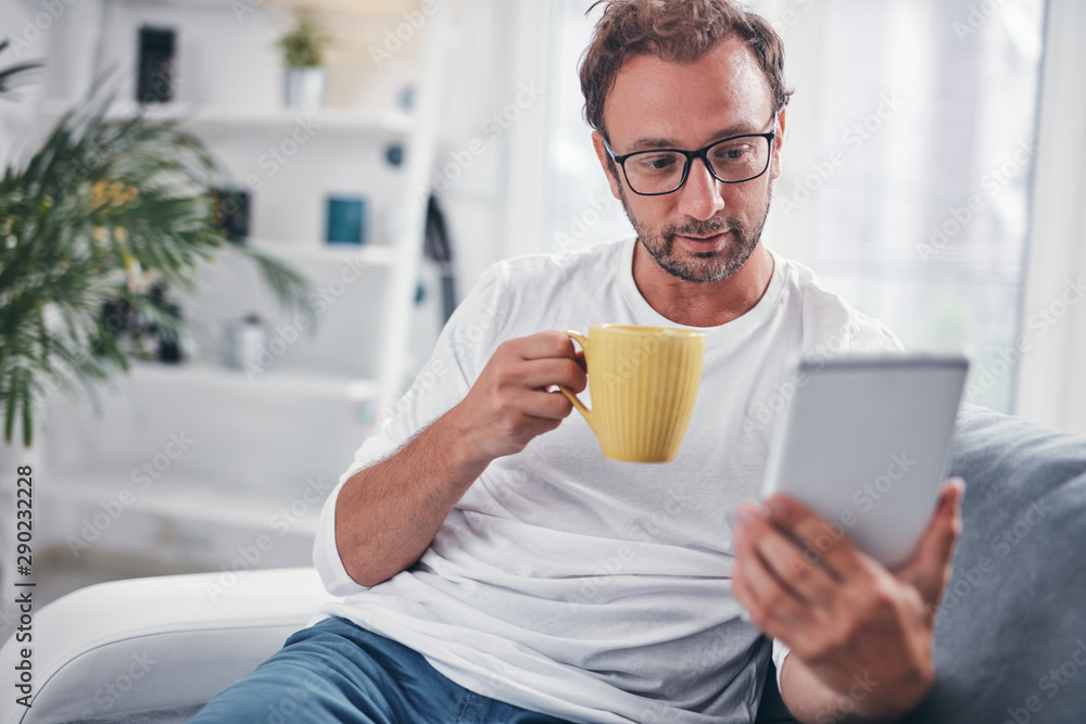 Man holding tablet, surfing online and drinking coffee. Man holding tablet, surfing online and drinking coffee.