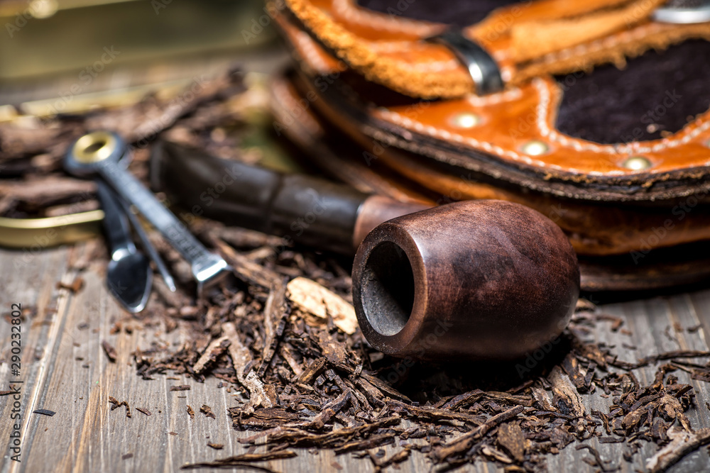 Wooden pipe with tobacco on wooden table. Tin boxes with tobacco, pipes and vintage background. Gentle man concept. Still life and prodoct photography.