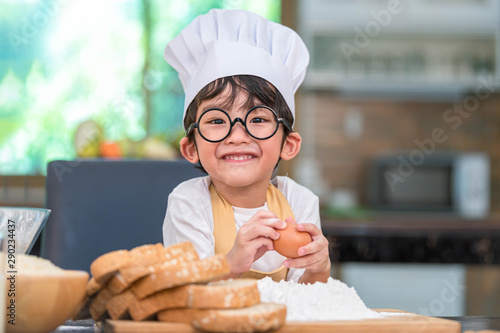 Portrait cute little Asian happy boy interested in cooking funny in home kitchen. People lifestyles and Family. Homemade food and ingredients concept. Baking Christmas cake and cookies. Smiling child
