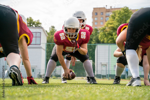 Image of sportive women playing american football on green lawn