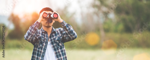 Man with binoculars telescope in forest looking destination as lost people or foreseeable future. People lifestyles and leisure activity concept. Nature and backpacker traveling jungle background photo