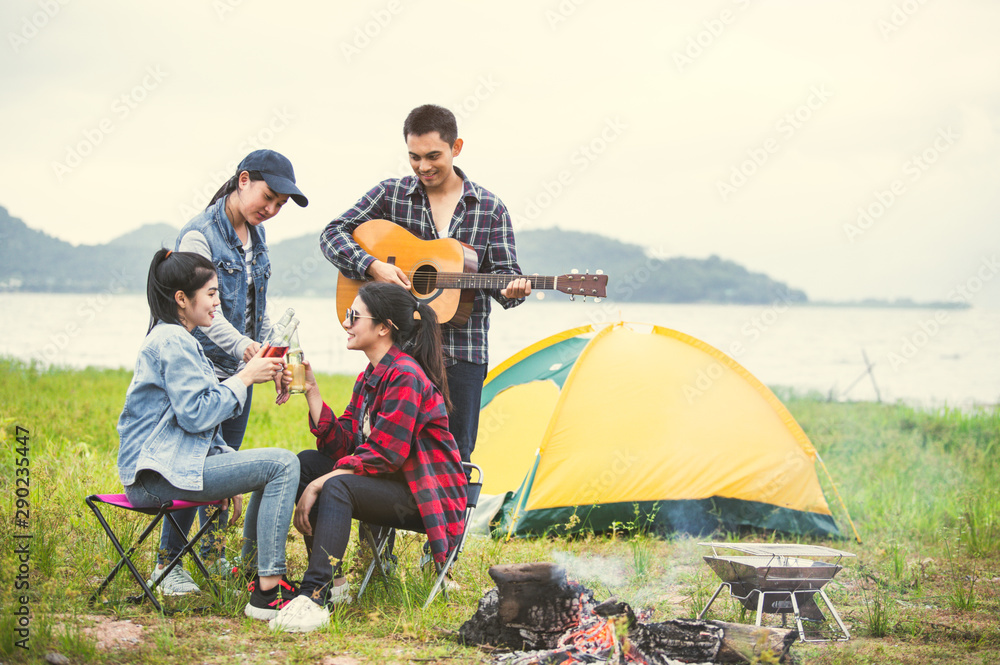 Group of Asian friendship clinking drinking bottle glass for celebrating in private party with mountain and lake view background. People lifestyle travel on vacation concept. Picnic and camping tent