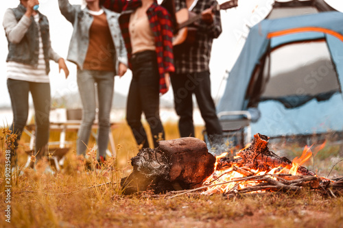 Closeup of campfire and friendship dancing to beat of the music for celebrating in party with mountain meadow and lake view background. People lifestyle and travel vacation. Picnic and camping tent