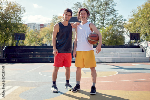 Full-length photo of two athletes with basketball on playground .