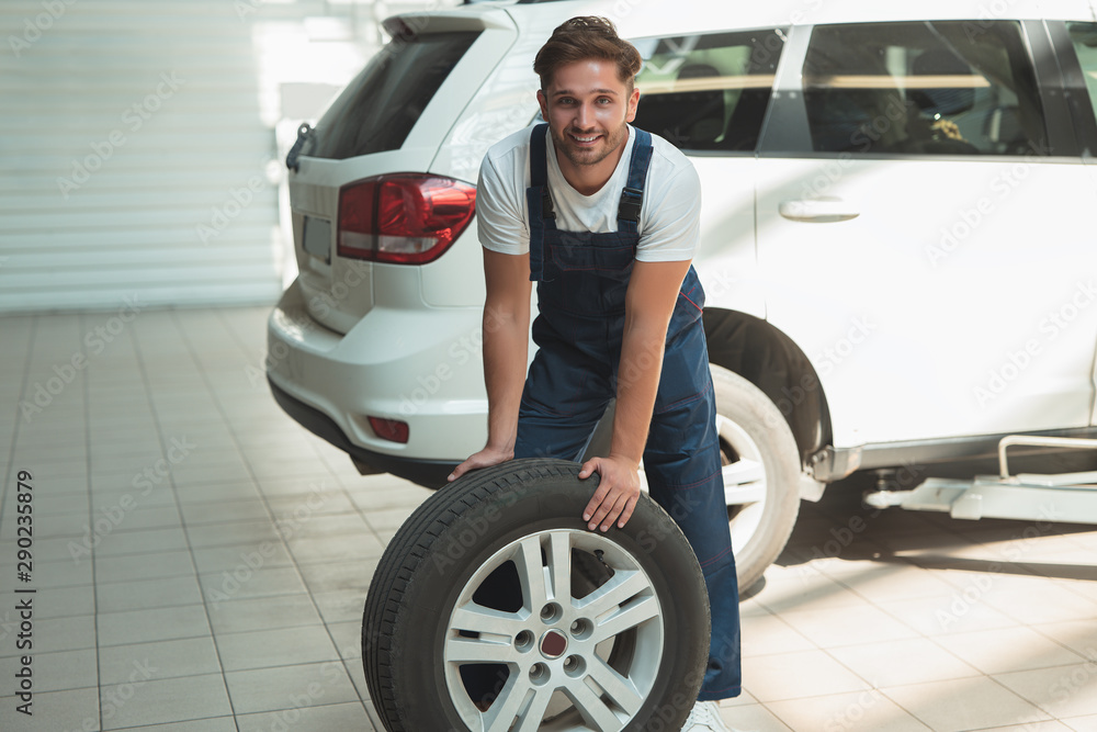 young handsome mechanic working in car service department fixing tire young handsome mechanic working in car service department fixing tire