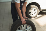strong hands of mechanic holding flat tire in car service department