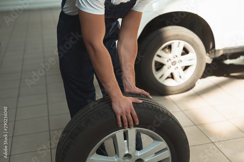 strong hands of mechanic holding flat tire in car service department