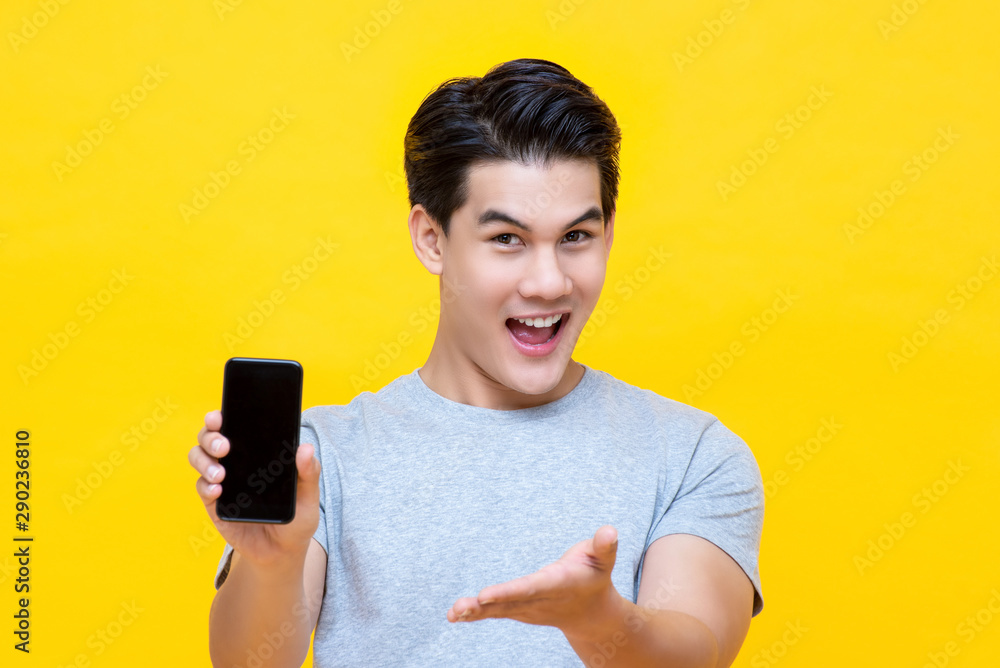 Smiled young good looking Asian guy showing smartphone Smiled young good looking Asian guy showing smartphone