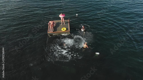 Cheerful teenagers are jumping into the sea. Aerial shot