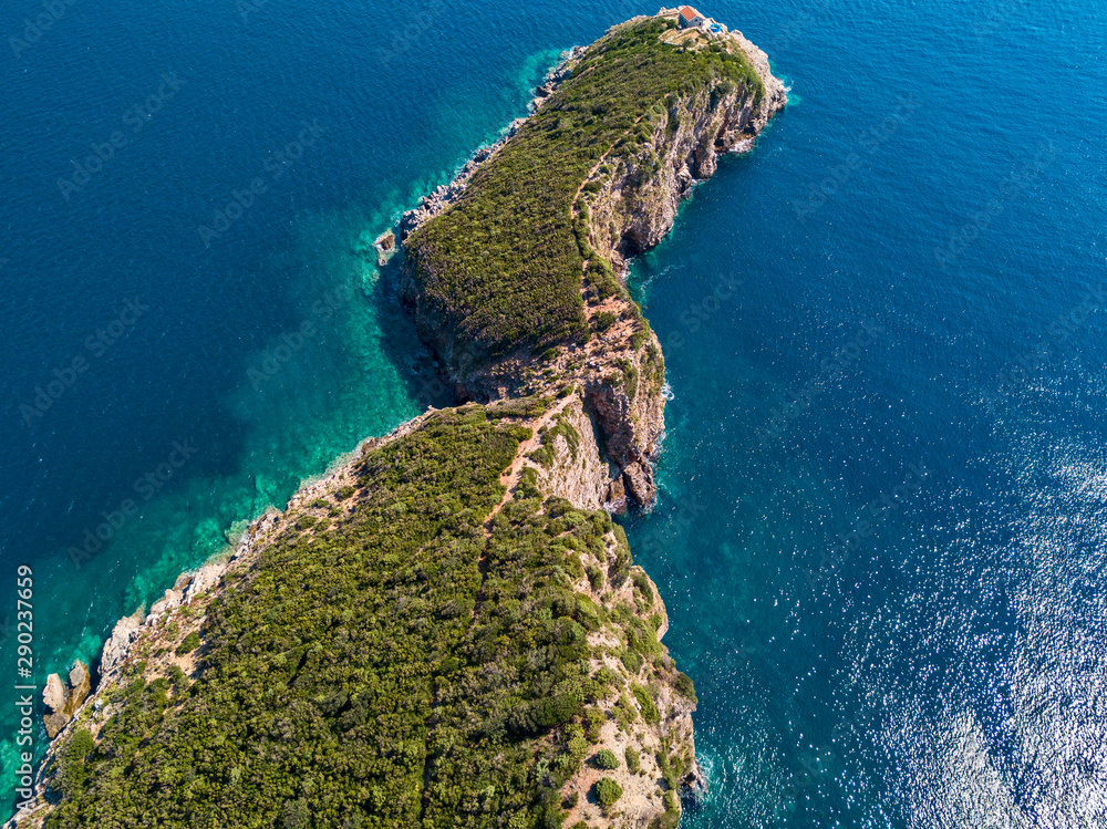 Aerial view of Sveti Nicola, Budva island, Montenegro. Hawaii beach, umbrellas and bathers and crystal clear waters. Jagged coasts with sheer cliffs overlooking the transparent sea. Wild nature