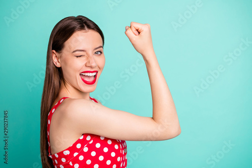 Close up photo of cheerful lady winking blinking her eyes raising fists screaming yeah wearign polka dot dress isolated over green teal turquoise background photo