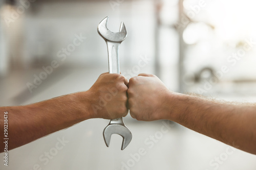two man fist bumping one with car spanner photo