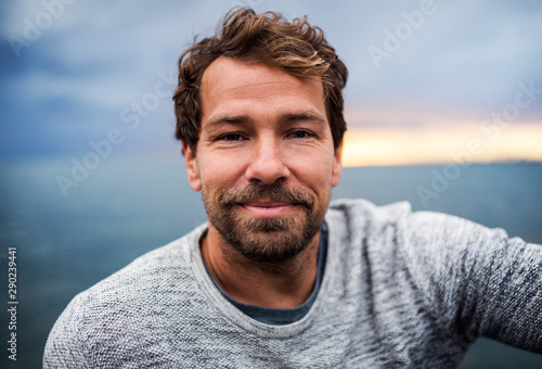 A portrait of handsome man standing outdoors, looking at camera.
