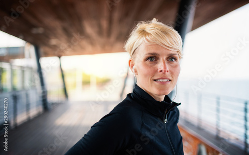 A portrait of young sportswoman resting after doing exercise outdoors. photo