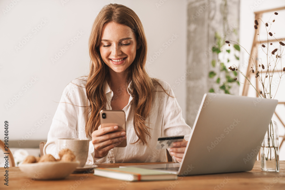 Woman using laptop computer and mobile phone holding credit card. Woman using laptop computer and mobile phone holding credit card.
