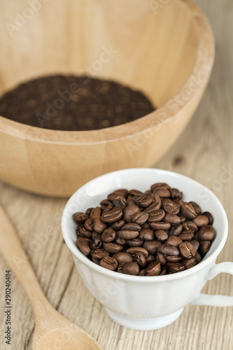 Coffee beans in coffee cup on wood table background.