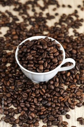 Coffee beans in coffee cup on wood table background.
