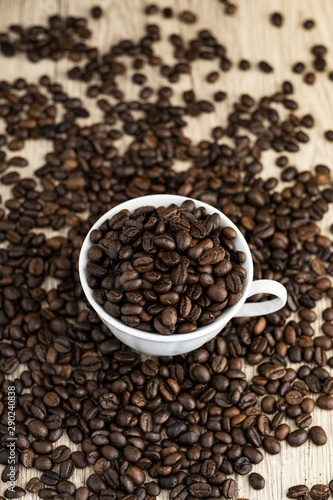 Coffee beans in coffee cup on wood table background. © TWINS DESIGN STUDIO