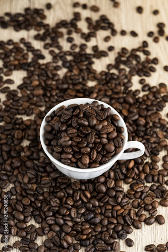 Coffee beans in coffee cup on wood table background.