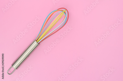 close up of colorful kitchen whisk on pink background