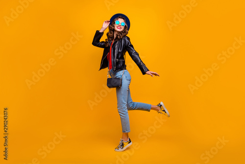 Full length photo of cute lovely lady enjoy her free time on stroll in autumn fall wear black leather jacket denim jeans isolated over yellow color background