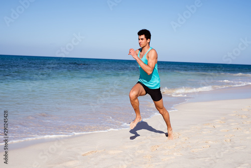 Young man running on a beach near the water
