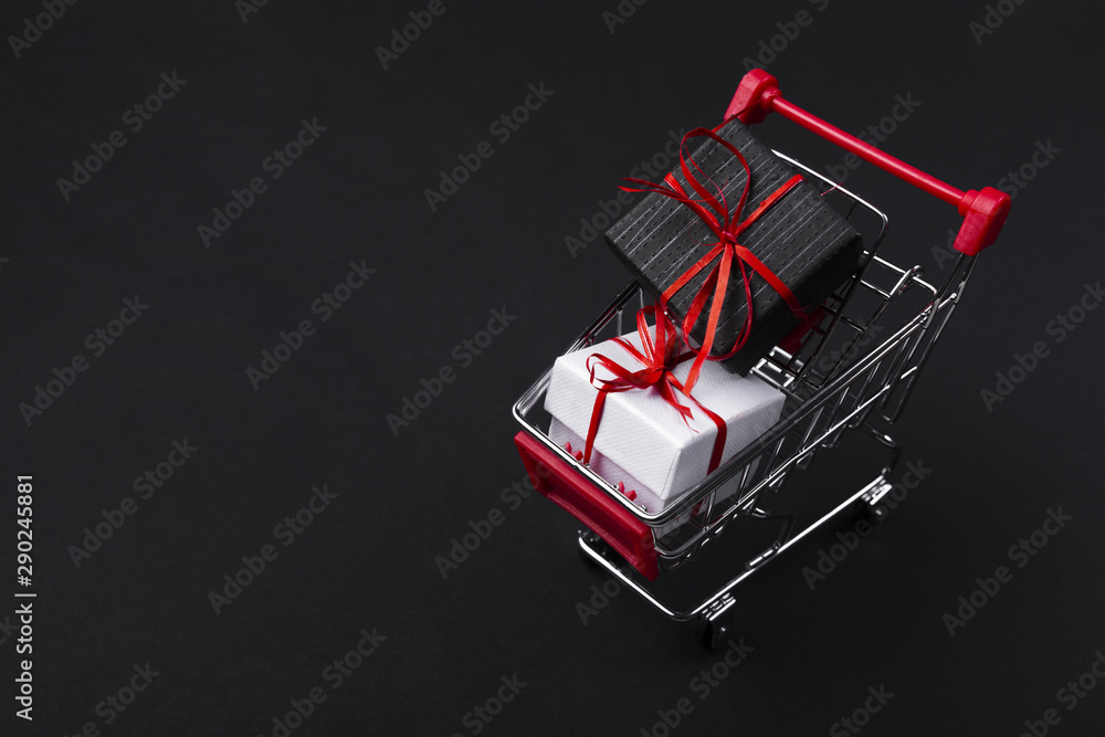 Naklejka premium Shopping cart with gifts on dark background