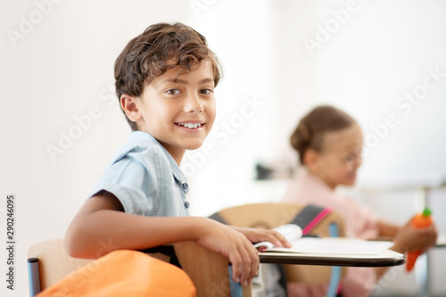Dark-eyed boy smiling while having little break at school